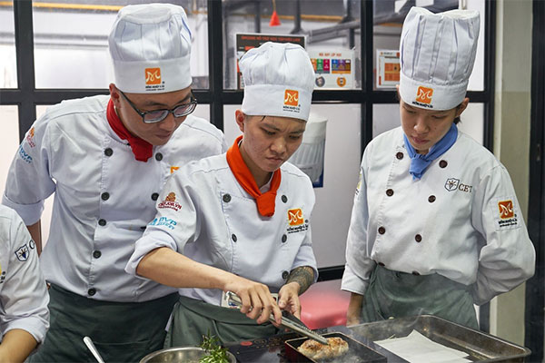 học viên tham gia cuộc thi nấu ăn với nguyên liệu chính là thịt heo trắng